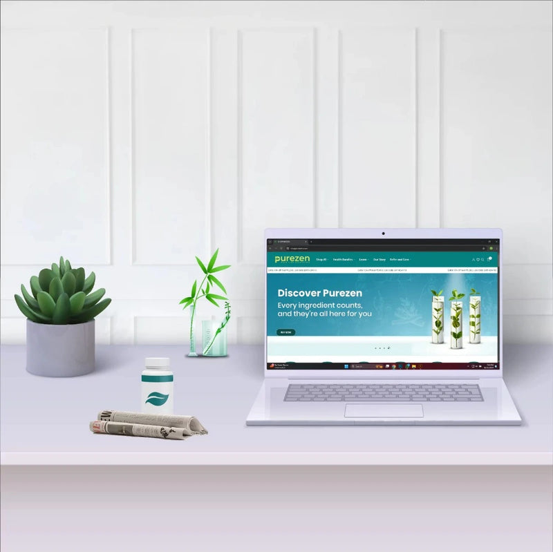 Laptop on a desk with Purezen website displayed, surrounded by plants and a cup.